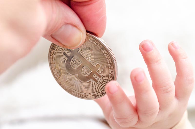 Blog Header Image. Parent Giving a Crypto coin to their baby